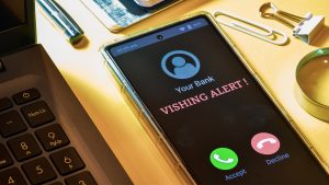 Smartphone screen showing phone call from bank with Vishing alert message. Phone call scam or phishing attacker asking for bank details.